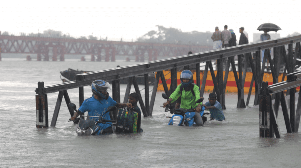 Two children push bikers who are trying to reach land from the Kalurghat Ferry Ghat on August 2, 2023. Photo: Mohammad Minhaj Uddin